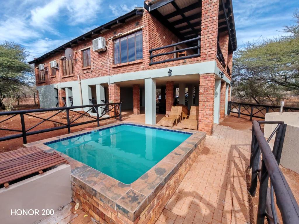 een bakstenen huis met een zwembad ervoor bij Lion's Pride - Marloth Park in Marloth Park