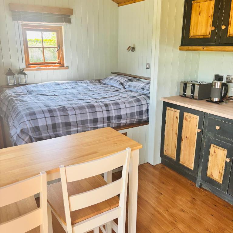 a small bedroom with a bed and a table and a kitchen at Stratford Bespoke Shepherd Hut in Snitterfield
