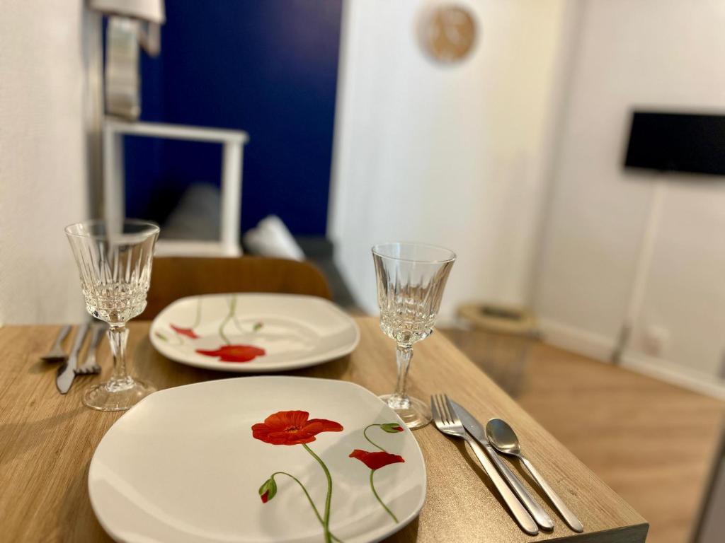 une table en bois avec deux assiettes et des verres dans l'établissement Bleu Nuit à Rouen - 390, à Rouen