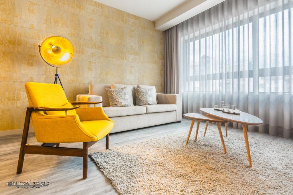uma sala de estar com uma cadeira amarela e um sofá em Passos Manuel by Innapartments no Porto