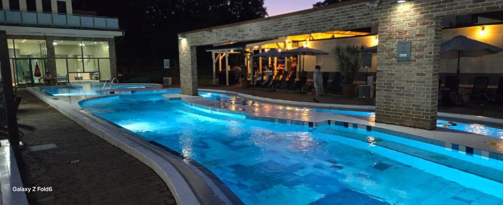 a swimming pool at night with blue lighting at Holiday Beach Budapest Wellness Hotel with Sauna Park in Budapest