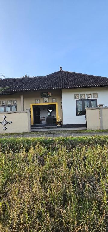 a house with a yellow and white building at Ibu Ana Homestay in Tabanan