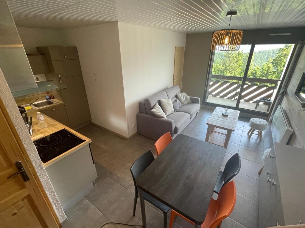une cuisine et un salon avec une table et un canapé dans l'établissement L Évidence, 4 à 5 couchages, 1 chambre, cellier, Meublé de Tourisme 3 étoiles, vue dégagée, parking gratuit, à Chamrousse