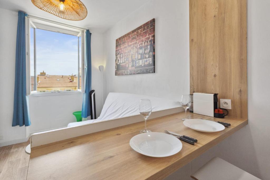 Cette chambre comprend une table avec deux verres et un lit. dans l'établissement L'Opéra - Hypercentre - Cosy - No elevator - Minimalist - Sea, à Nice