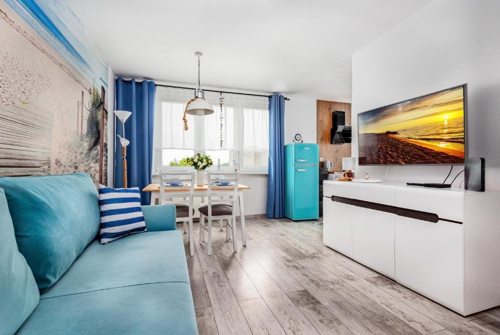 Una sala de estar con un sofá azul y una cocina. en Apartament Lokum, en Władysławowo