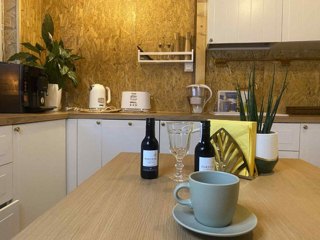a table with two bottles of wine and a coffee cup at Solne Apartamenty Luna 4 in Wieliczka