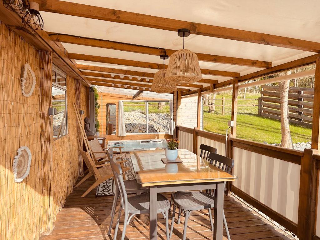 une salle à manger avec une table et des chaises sur une terrasse dans l'établissement 2 chambres à 15 mn de la mer en pleine nature Jacuzzi dispo du 01 avril au 15 octobre, à Anneville-sur-Scie