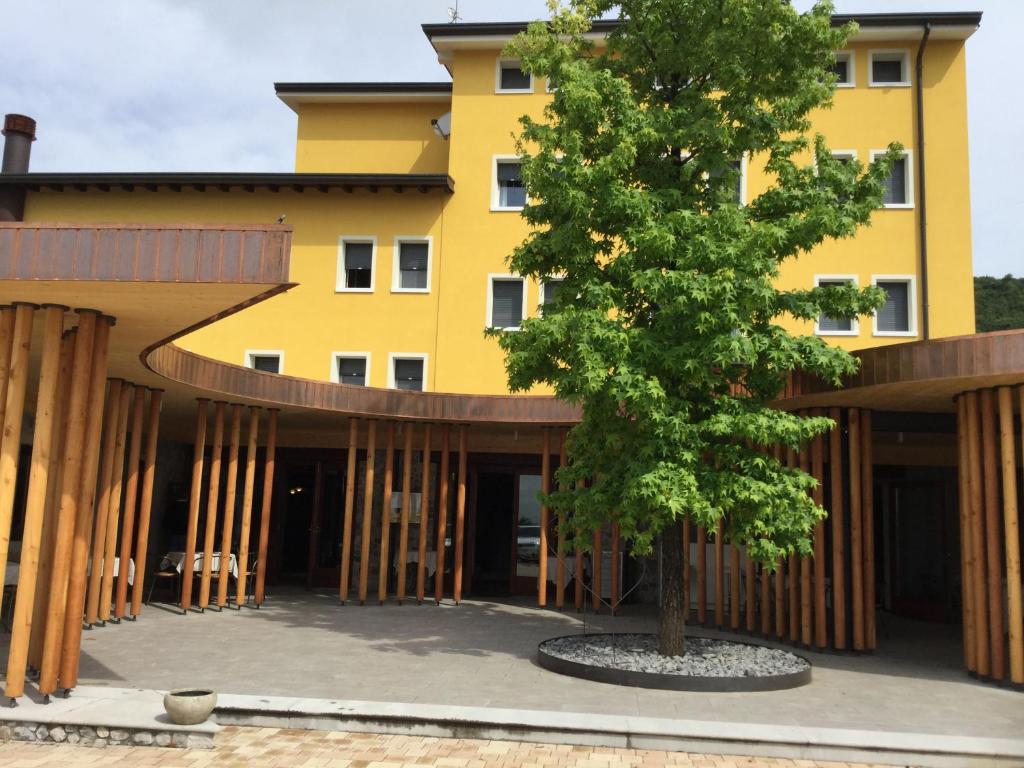 ein gelbes Gebäude mit einem Baum davor in der Unterkunft Albergo Belvedere in Sequals