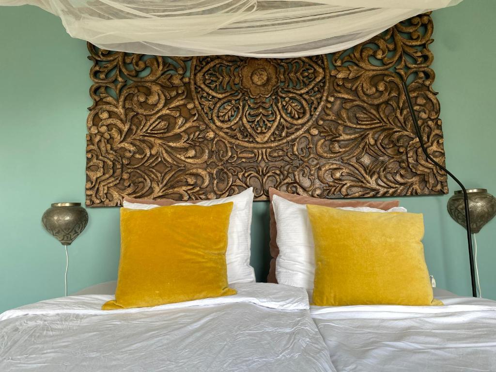 a bed with two yellow pillows and a headboard at B&B Bakenberg in Arnhem