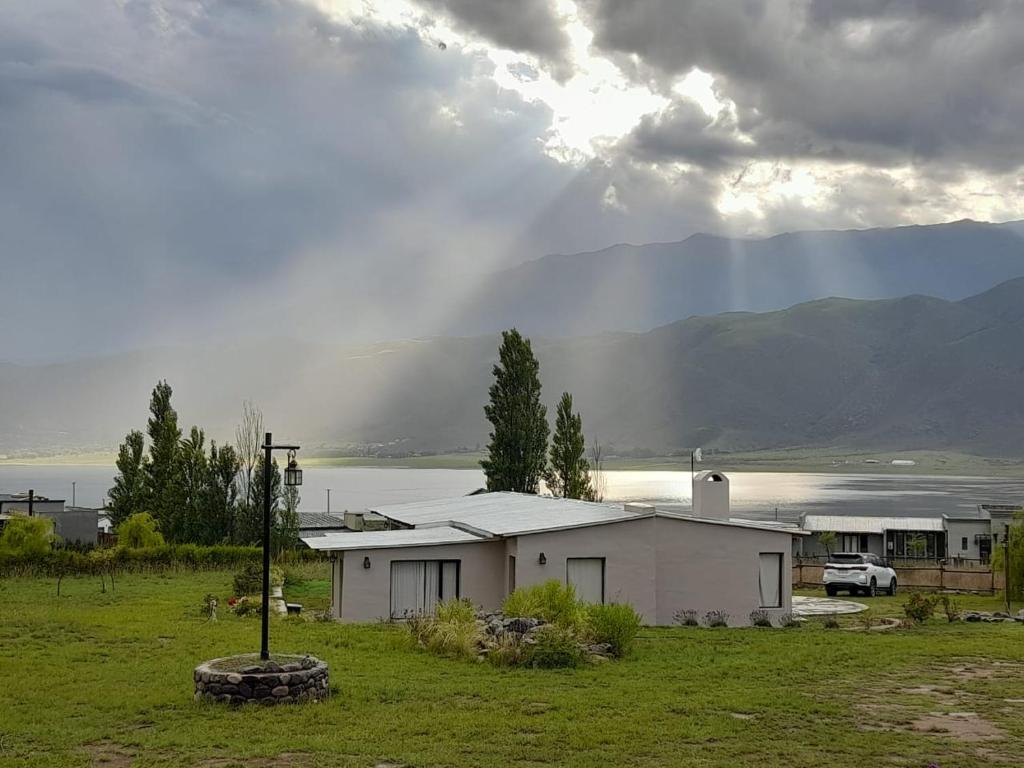 a small white house in a field with a mountain at La escondida las siringuillas in Tafí del Valle