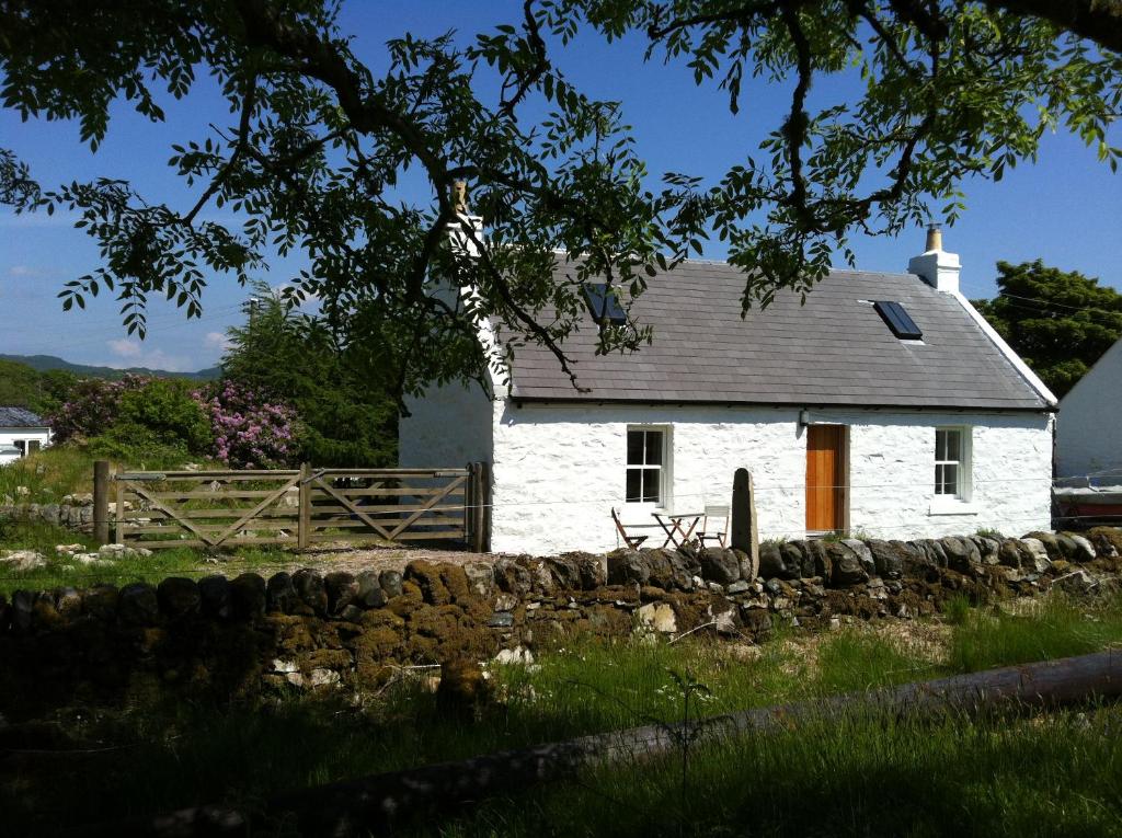 ein weißes Haus mit einem Zaun davor in der Unterkunft Cnocachanach Cottage in Tarbert