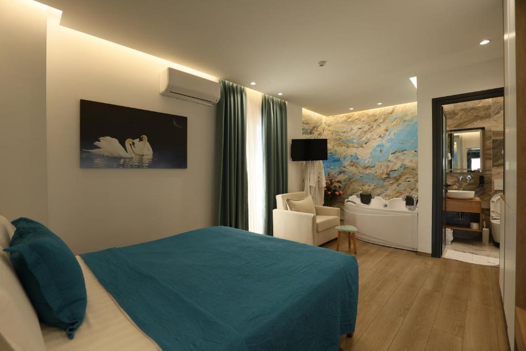 a bedroom with a blue bed and a bathroom at Ilio Boutique Hotel in Ksamil