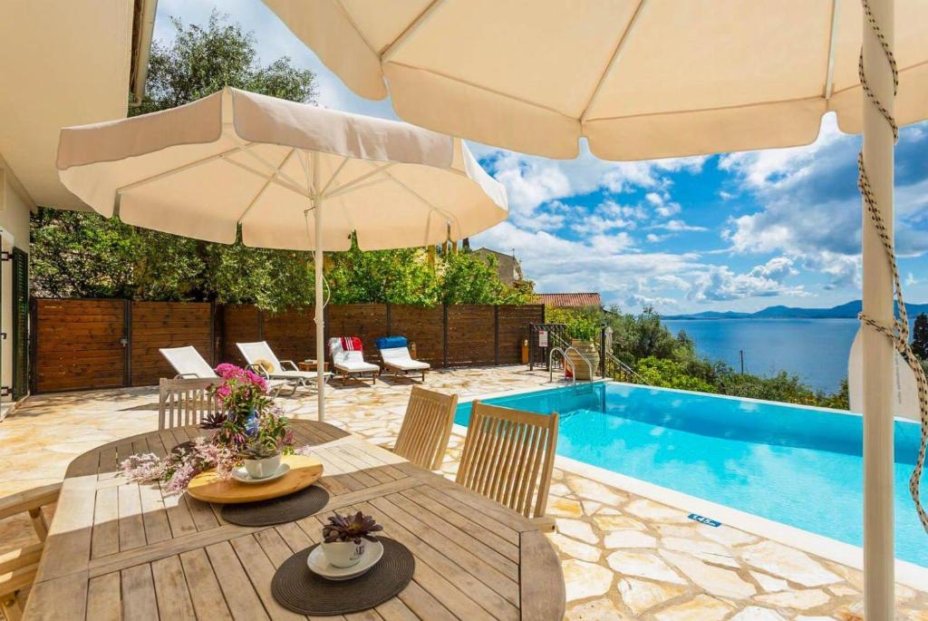 een tafel met een parasol naast een zwembad bij Villa Katerina in Katávolos