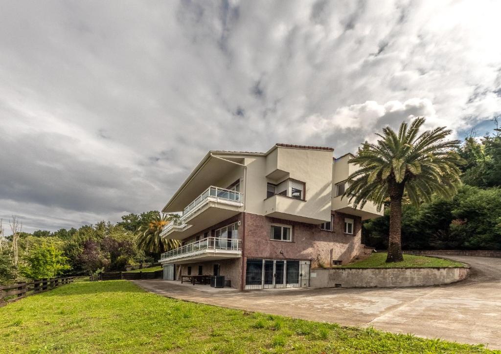 a house with a palm tree in front of it at Aston - Villa Islas Urdaibai in Isla Becoa