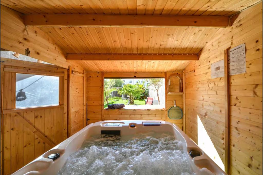 bañera en una habitación de madera con ventana en Velours 4 & Jacuzzi, en Saint-Nazaire