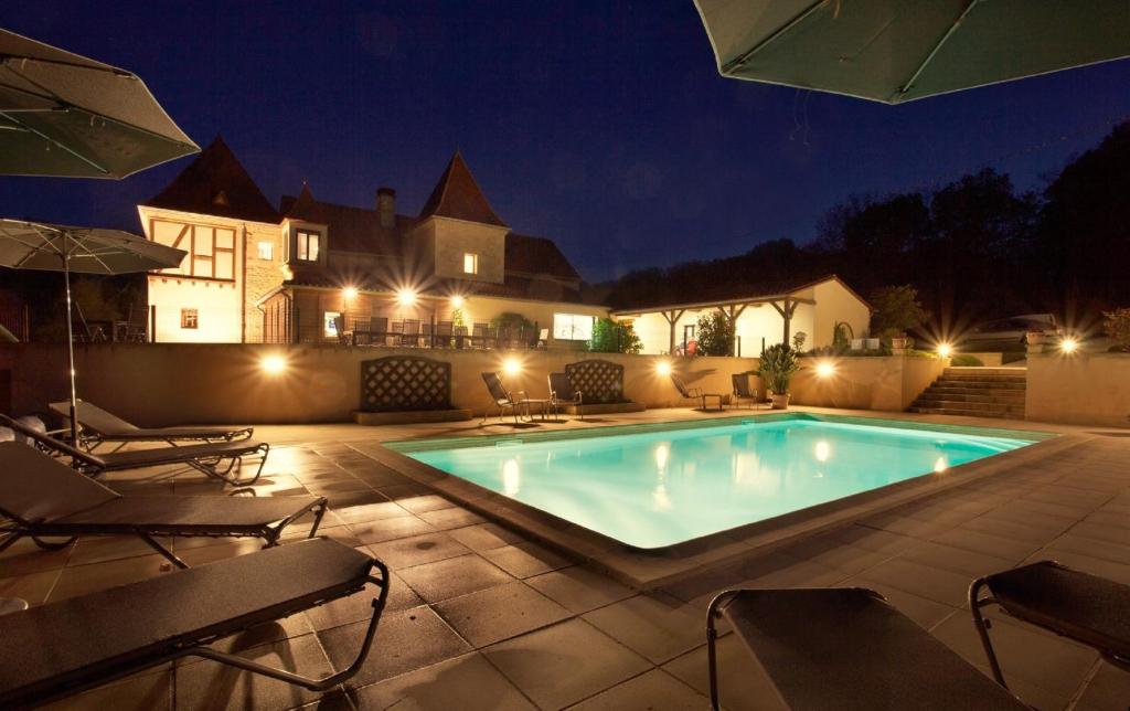 a swimming pool in front of a house at night at Chambres d'hôtes Les Peyrouses in Sarlat-la-Canéda