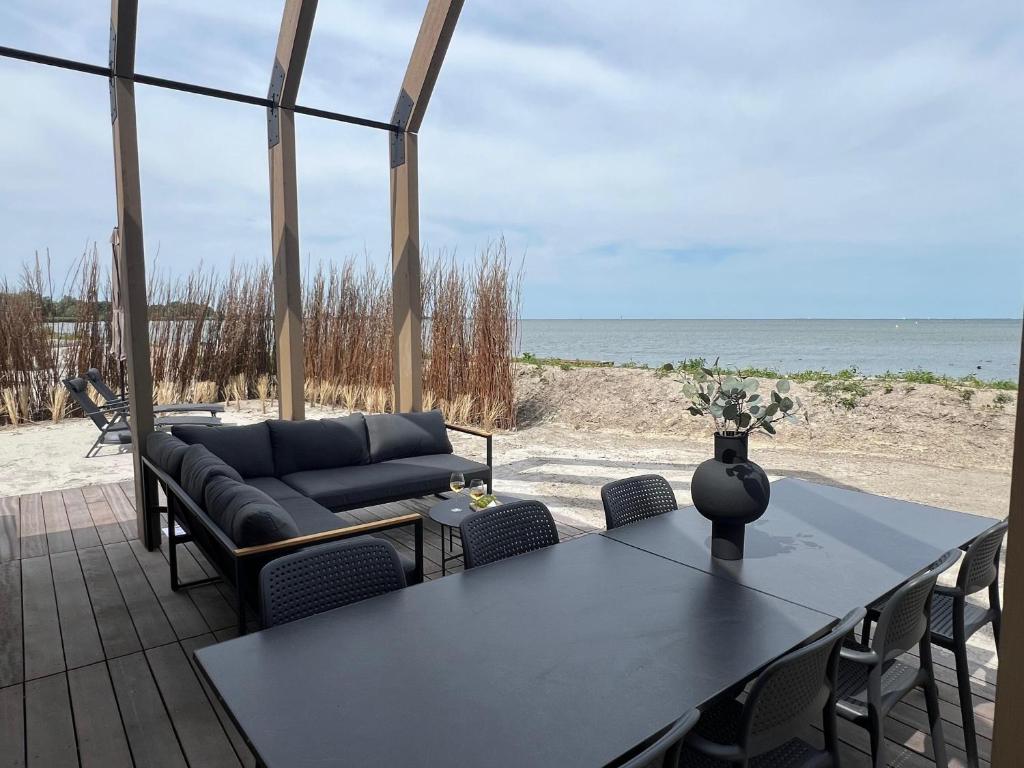 un soggiorno con divano, tavolo e spiaggia di Enkhuizer Strand BeachHouse Odyssee Nr 513 a Enkhuizen