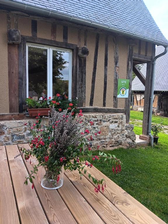 a vase of flowers sitting on a wooden table at Le Grenier in Saint-Christophe-sur-Condé