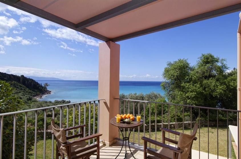 a balcony with two chairs and a table with fruit on it at Villa Ithaki Kefalonia in Lourdhata