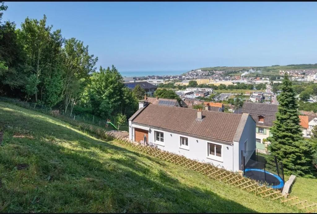 une maison blanche au sommet d'une colline verdoyante dans l'établissement Maison confortable avec jardin à Le Tréport, au Tréport