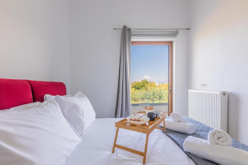 een slaapkamer met een wit bed en een tafel met handdoeken bij Stella by Hospi in Kato Gouves