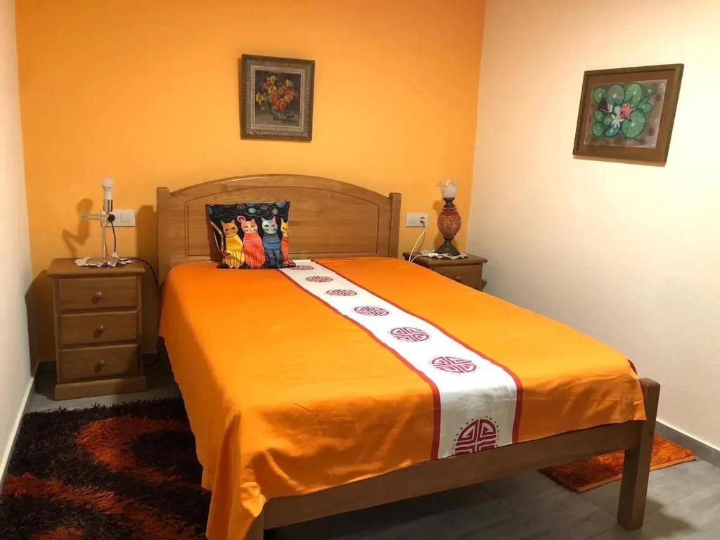 ein Schlafzimmer mit einem Bett mit einer orangefarbenen Decke in der Unterkunft Cozy house near Lobios, 92 m², nature in Lobios