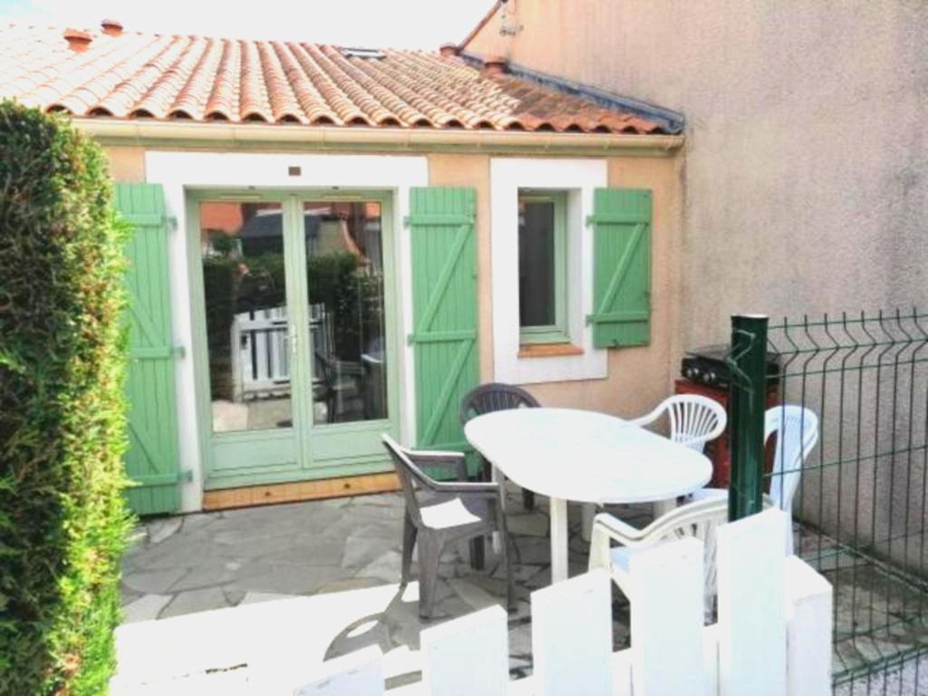 un patio avec une table et des chaises devant un bâtiment dans l'établissement maison Valras Plage - Résidence Lou Portalou, à Valras-Plage