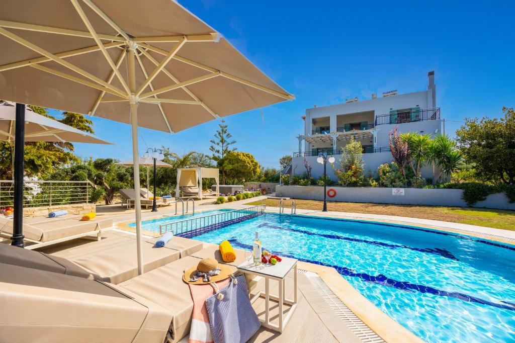 ein Pool mit Sonnenschirm und Stühlen sowie ein Gebäude in der Unterkunft Villa Kyveli in Loutra