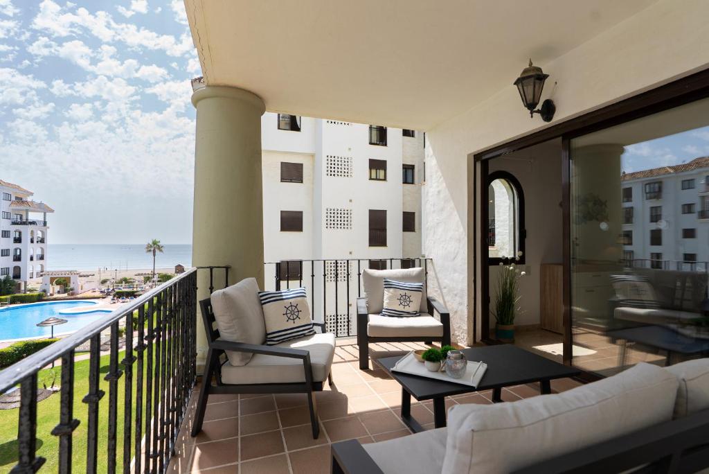a balcony with two chairs and a table and a pool at 327 marina duquesa in Manilva