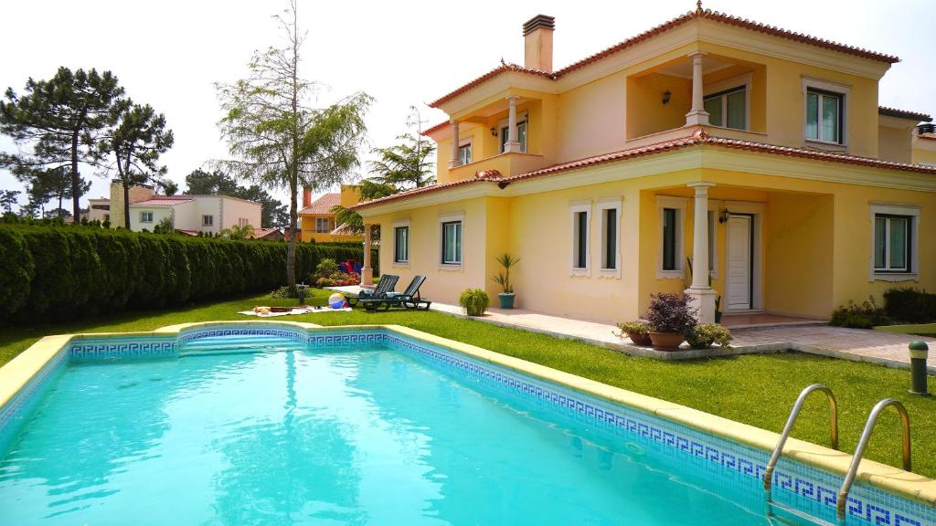 a house with a swimming pool in front of it at Casa Amarela - O seu Oásis na floresta in Praia de Mira