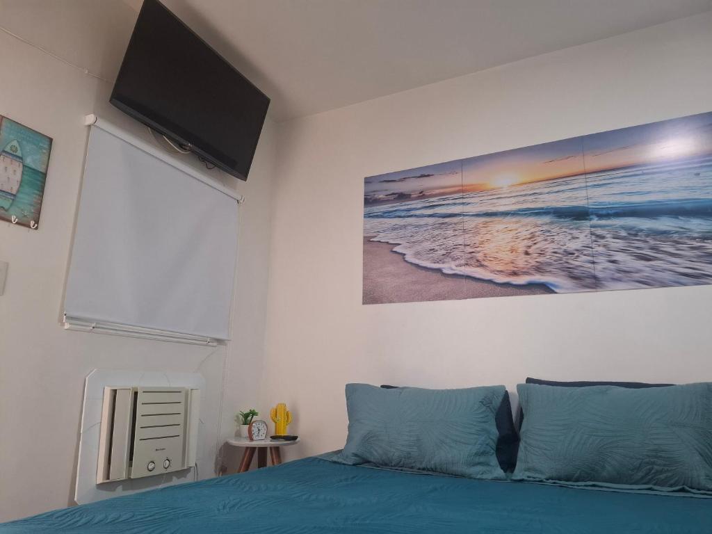 una camera con un letto blu e un dipinto sul muro di Como uma onda no mar a Rio de Janeiro
