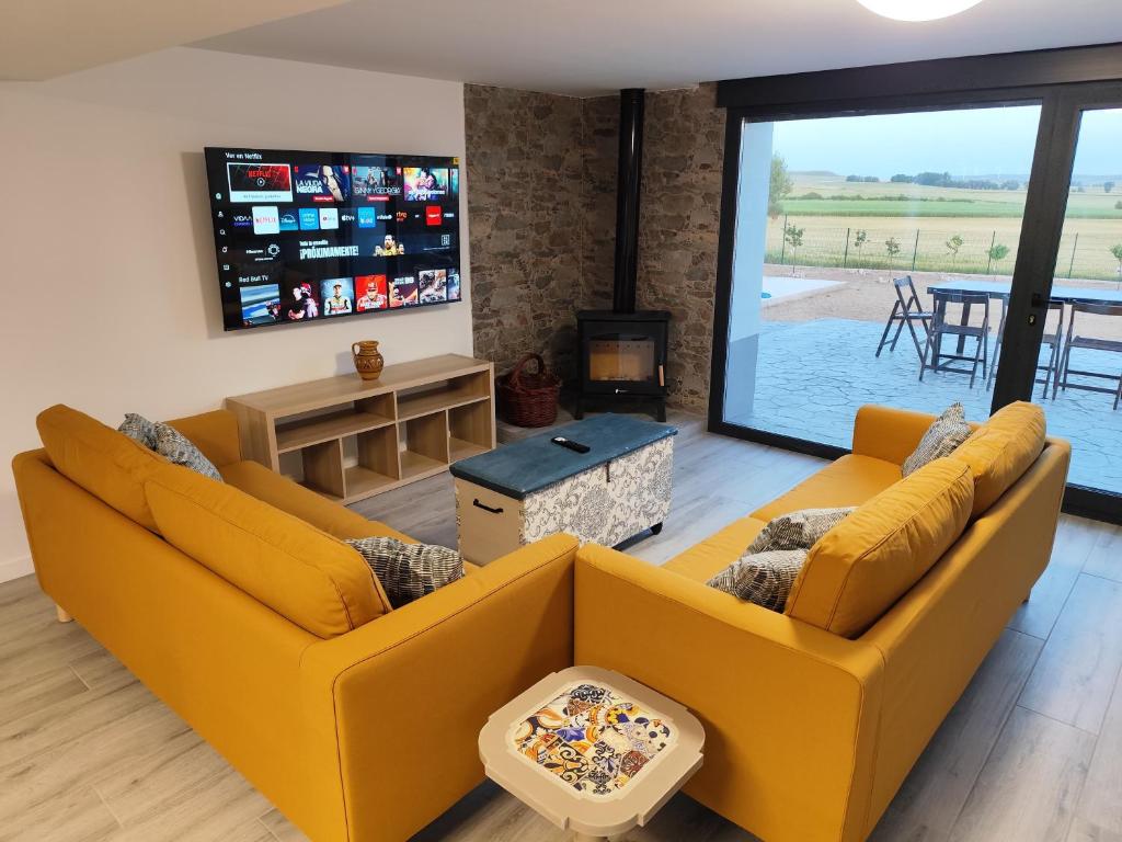 ein Wohnzimmer mit zwei Sofas und einem Fernseher in der Unterkunft Campos de Villalba in Villalba