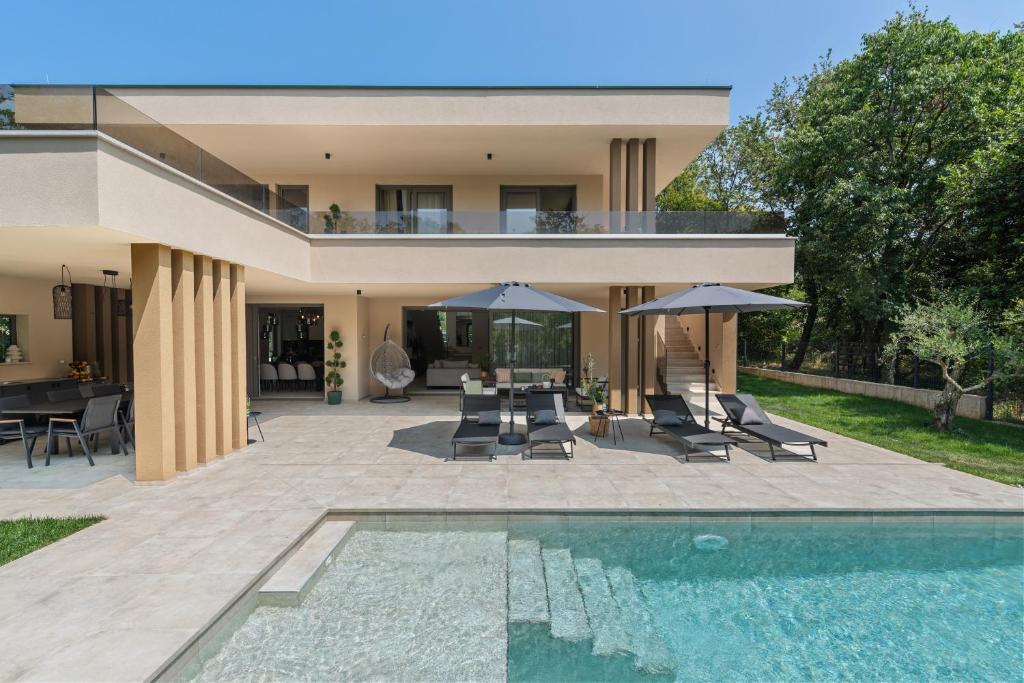 a house with a swimming pool and a patio with umbrellas at Villa Boschetto by SeeAdria Agency in Čepljani