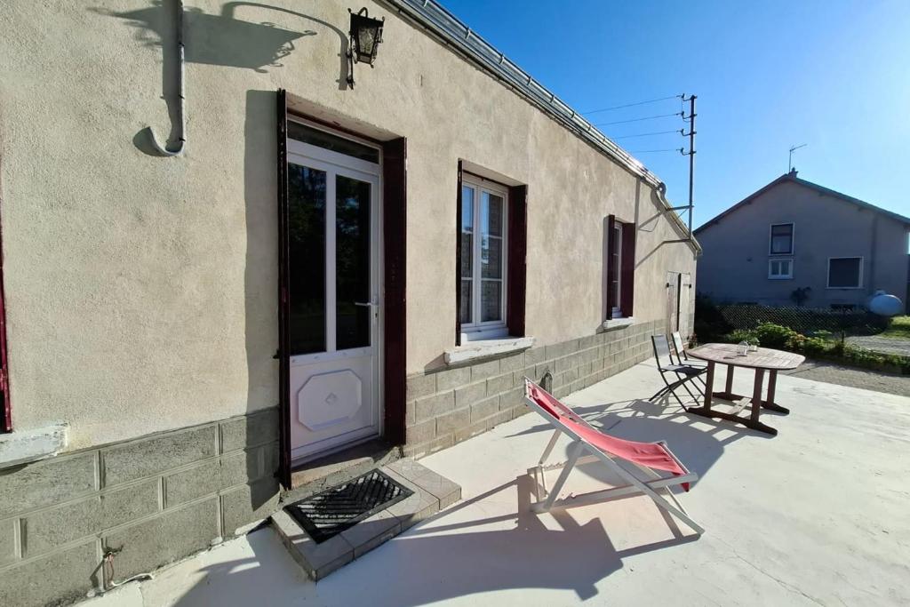 a patio with a table and chairs next to a building at Escapade à Éguzon Maison 3 chambres in Éguzon-Chantôme