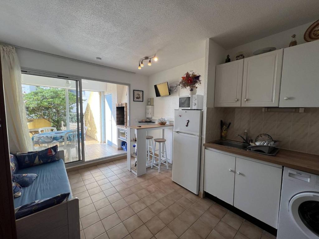 une cuisine avec des armoires blanches et une cuisine avec un balcon dans l'établissement Appartement T2 avec Terrasse, Proche Plage, Le Barcarès - FR-1-81-589, au Barcarès