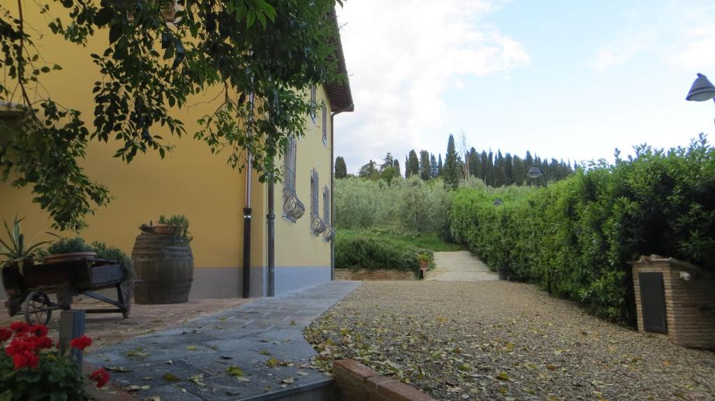 a pathway leading to a yellow building with a garden at Casale Poggimele in Empoli