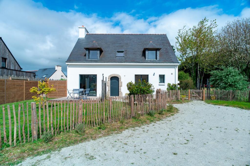 una casa blanca detrás de una valla de madera en Le Haut du Nelud - Appt dans maison avec jardin, en Locmariaquer