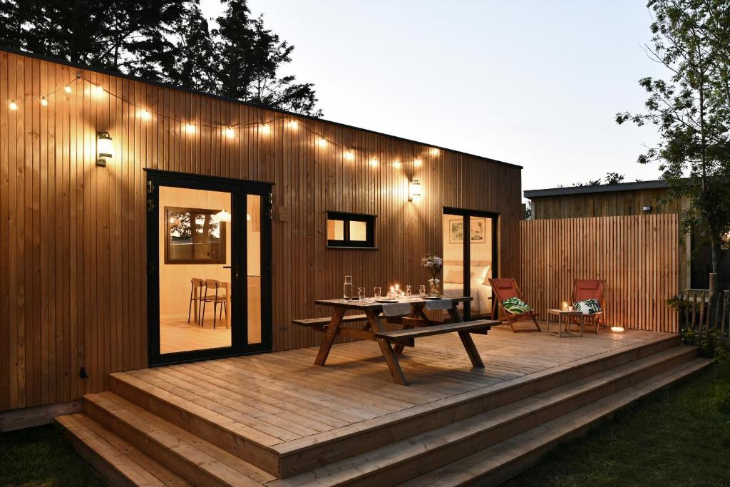 a house with a wooden deck with a table at O Lodge les jardins d iode proche mer in La Brée-les-Bains