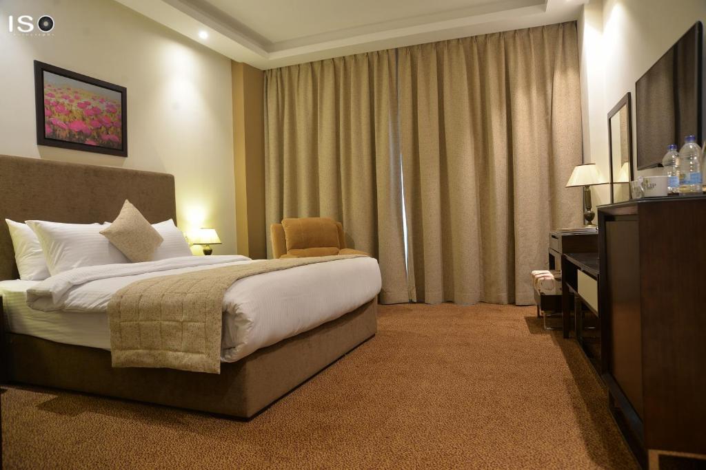 a hotel room with a large bed and a chair at Tolip El Narges in Cairo