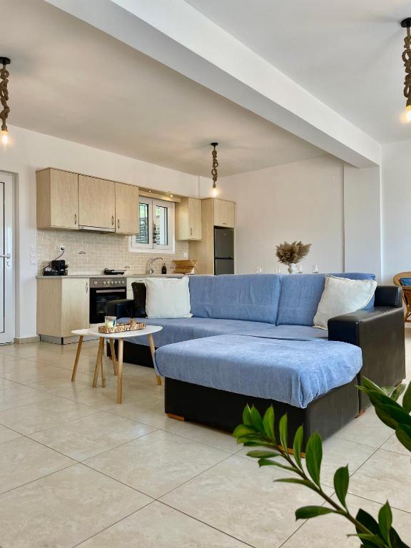 a living room with a blue couch and a kitchen at Aura Seaside Afrathias in Kalamaki