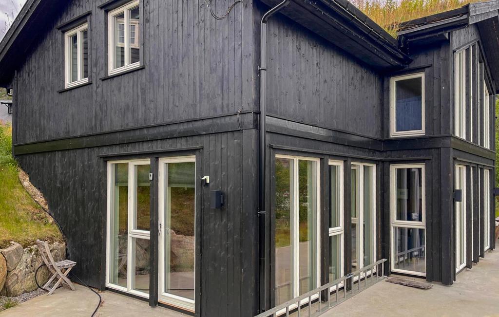 a black house with glass doors and windows at Cozy Home In Hovden I Setesdal - With Jacuzzi in Hovden