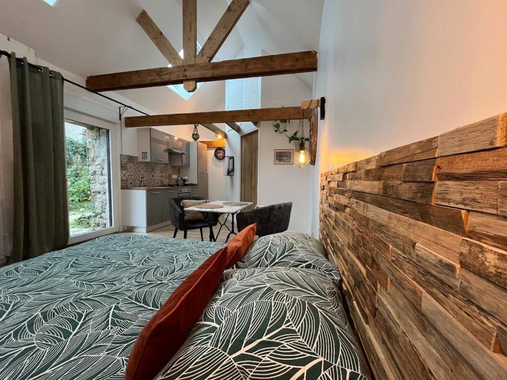 1 dormitorio con 1 cama grande y pared de madera en La Grange de Marcel, en Saint-Pol-de-Léon