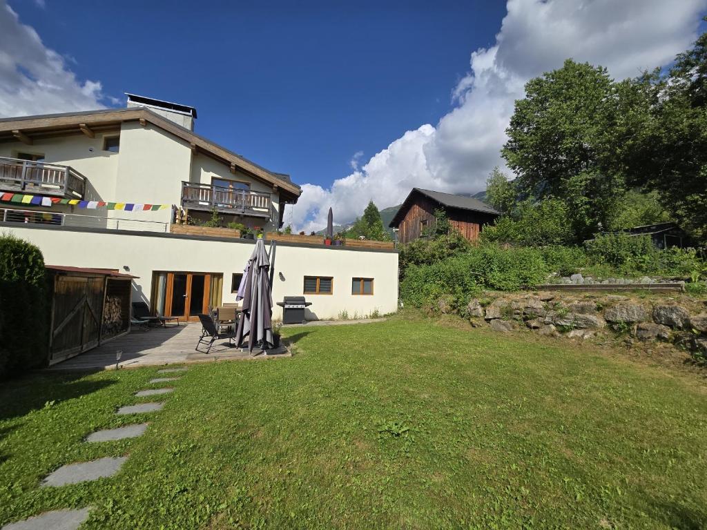 une maison avec une cour dotée d'un parasol devant elle dans l'établissement Pierre Belle - 80m2 - Grande Terrasse et Jardin, à Chamonix-Mont-Blanc