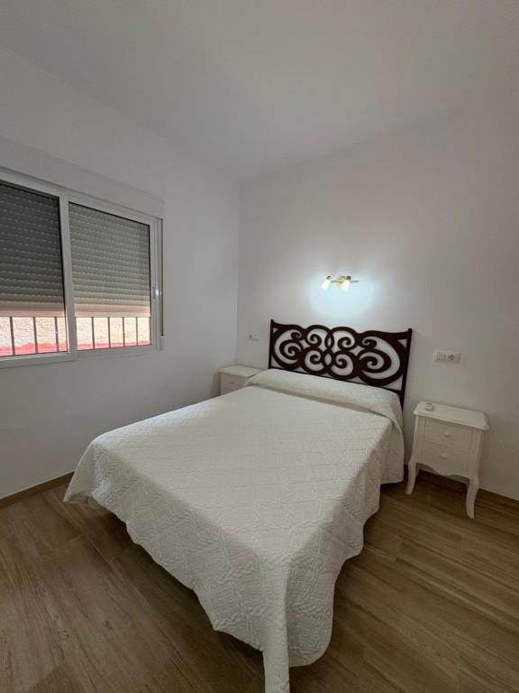 a white bedroom with a large bed and two windows at Apartamentos Cervera in Teulada