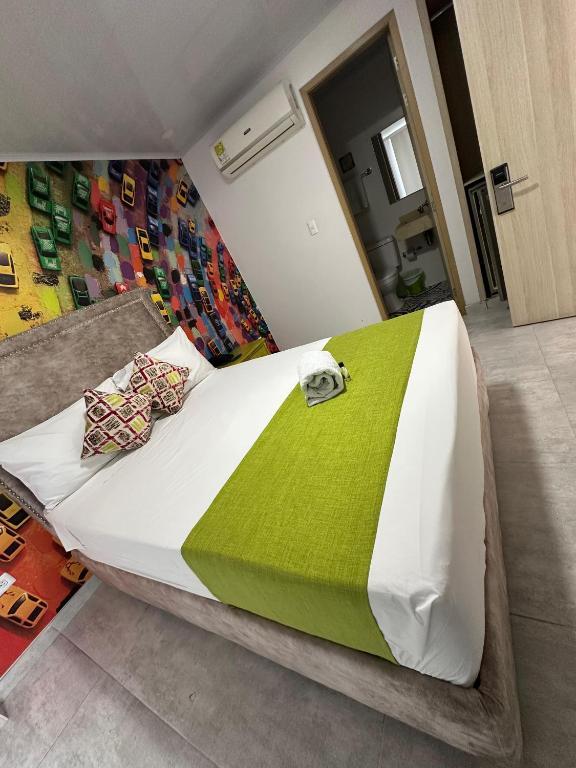 a bedroom with a large bed with a green blanket at Hotel Millenium Victoria Plaza in Cúcuta
