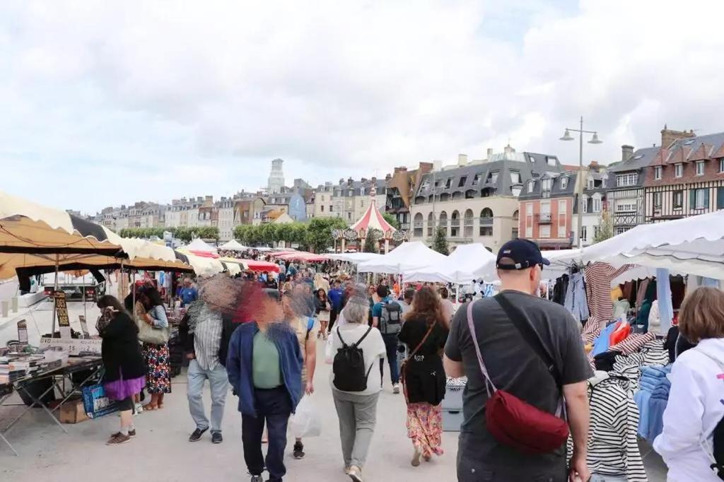 a crowd of people walking around an outdoor market at Hébergement design proche plage in Trouville-sur-Mer