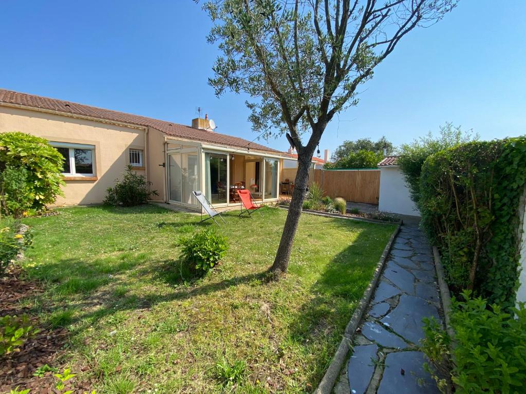 une maison avec un arbre dans la cour dans l'établissement Le Frangipanier, à Les Sables-dʼOlonne