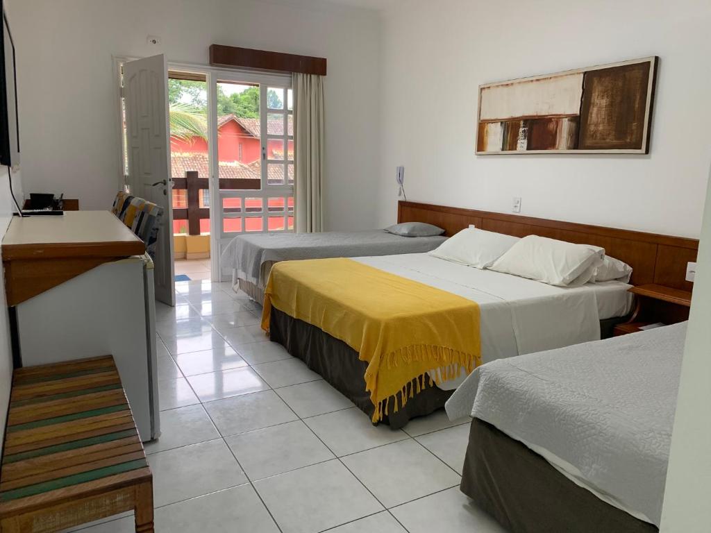a hotel room with two beds and a balcony at Riviera- Hotel Suite Família in Riviera de São Lourenço