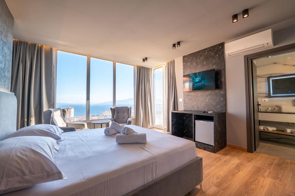 a bedroom with a large white bed with a large window at Ersa Luxury Rooms in Sarandë