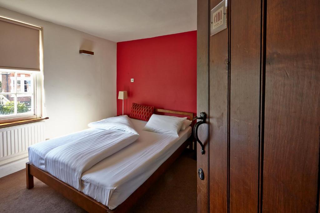 a bedroom with a bed with a red wall at Cini in Leicester